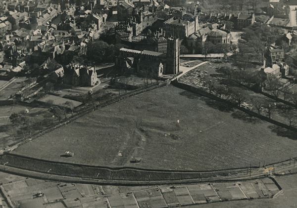 black and white aerial photo showing traces of earthworks in a field on the side of a hill.